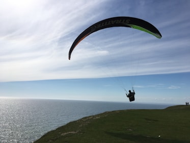 A paraglider soaring over a scenic coastline.