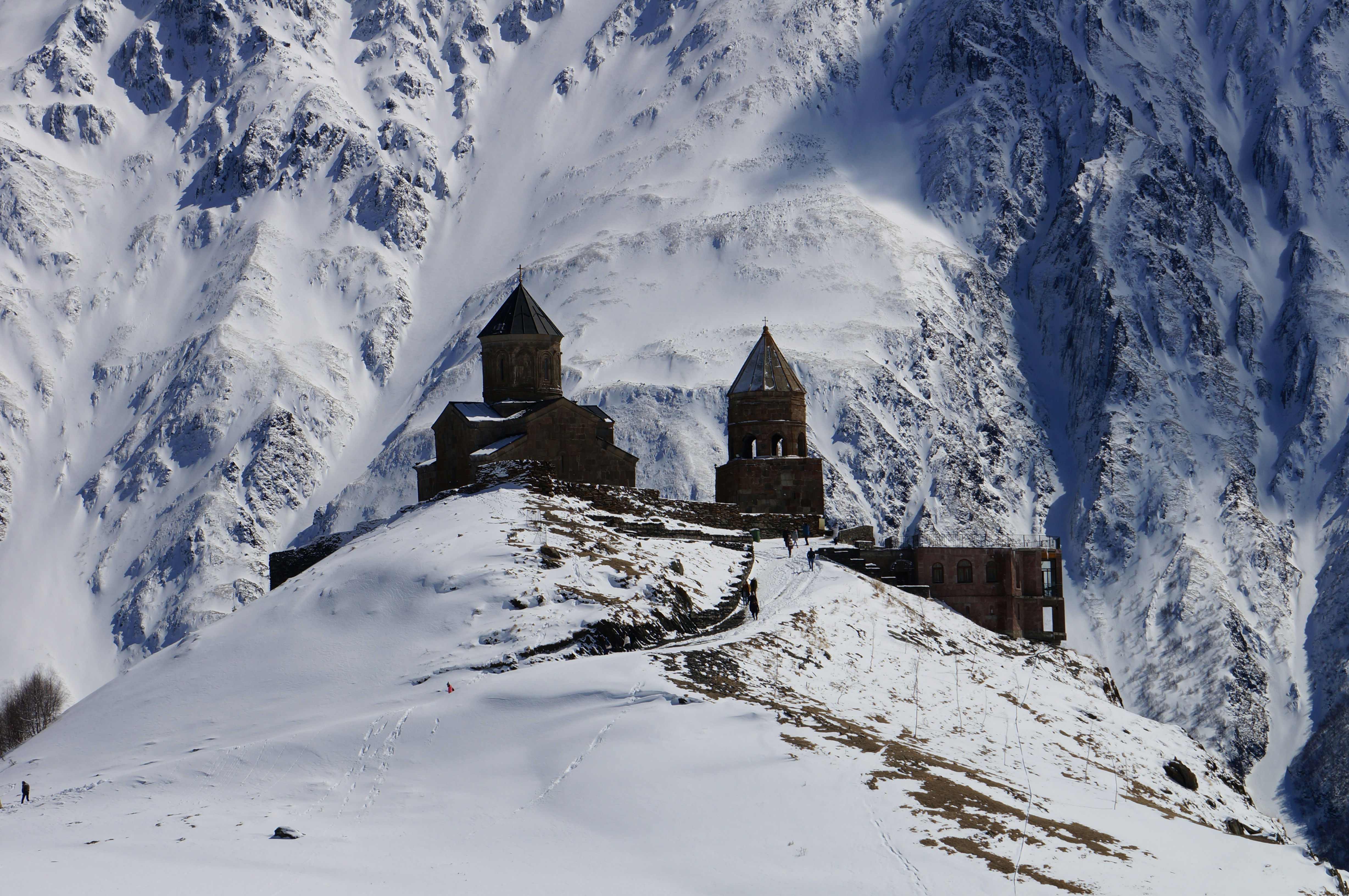 brown concrete house near snow covered mountain during daytime, Late March 2017 in Georgia. From the town of Kazbegi we took a 4x4 and after a 30 minutes rough ride through the snow and over muddy roads, we arrived at the Tsminda Sameba Church. The church is situated on a hilltop against the snow covered cone of Mt. Kazbeg. One of the highlights of our trip to beautiful Georgia.