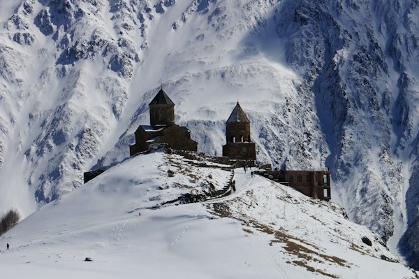Brown concrete house near snow covered mountain during daytime — Kazbegi, Georgia