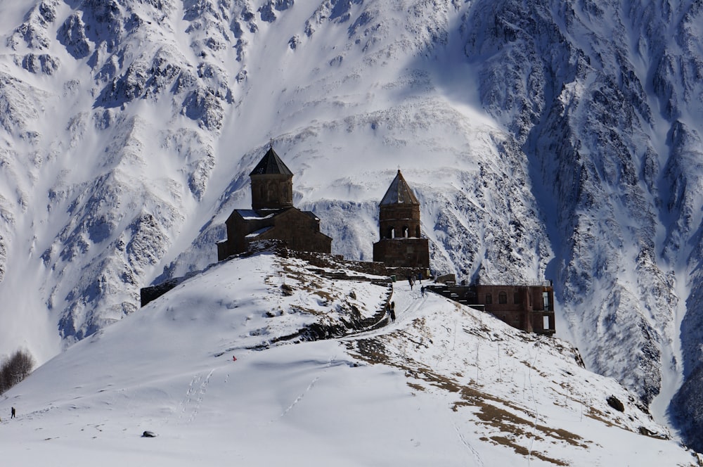 brown concrete house near snow covered mountain during daytime