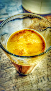 An inviting espresso shot with crema, placed next to a bilardo table in a warm cafe setting