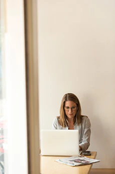 A focused woman working on her laptop surrounded by content planning tools and notes.