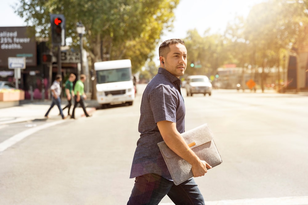 man holding bag walking on road