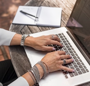 person typing on MacBook Pro on brown wooden table during daytime photo