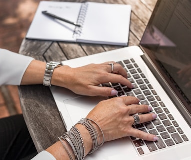 person typing on MacBook Pro on brown wooden table during daytime photo