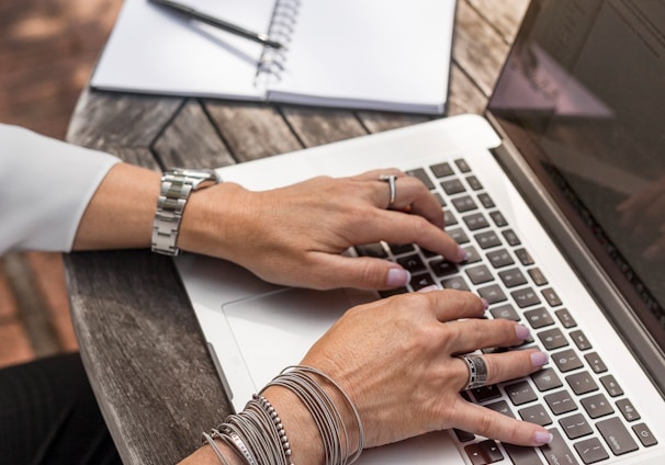 person typing on MacBook Pro on brown wooden table during daytime photo