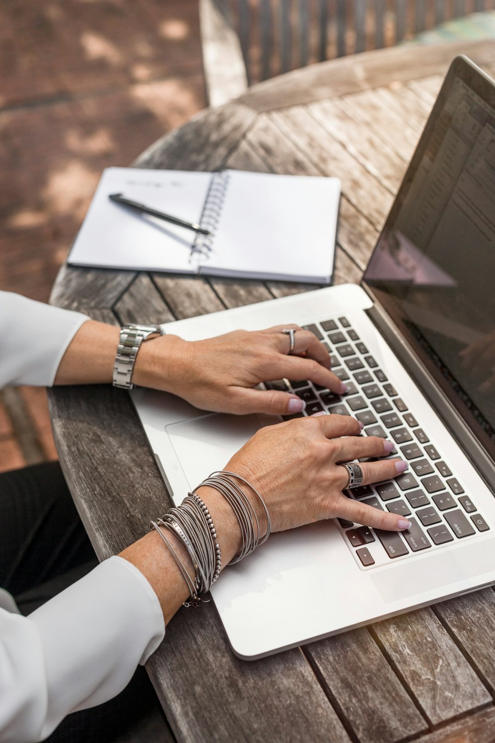 person typing on MacBook Pro on brown wooden table during daytime photo