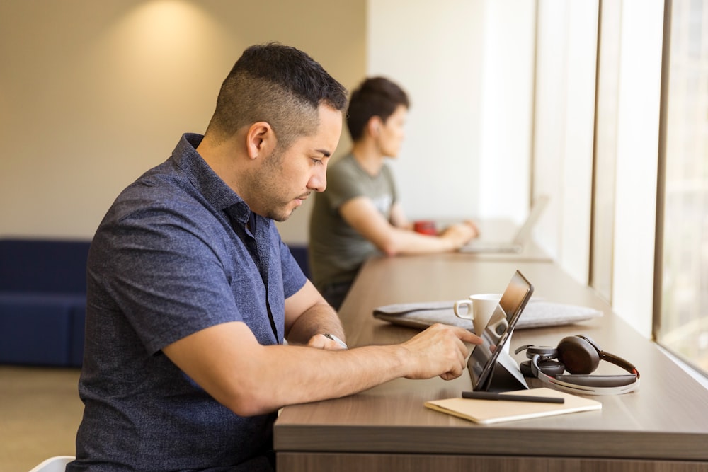 man touching tablet computer on desk