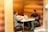 Two people are seated at a small, modern table in a cozy booth with cushioned benches. They are engaged in discussion, with one person using a laptop and the other taking notes. The booth is enclosed with warm-colored walls, creating an intimate meeting space.