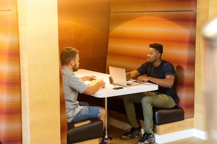 two guys in a booth undergoing a real estate coaching meeting 
