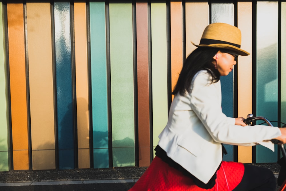 woman wearing white blazer and brown hat riding bicycle