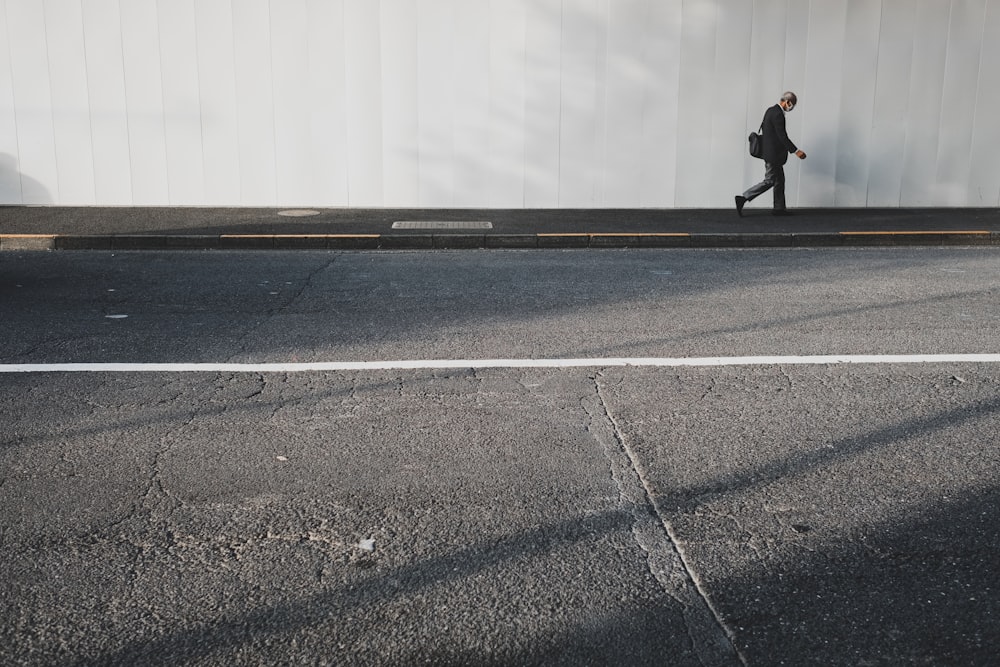 person walking near white wall