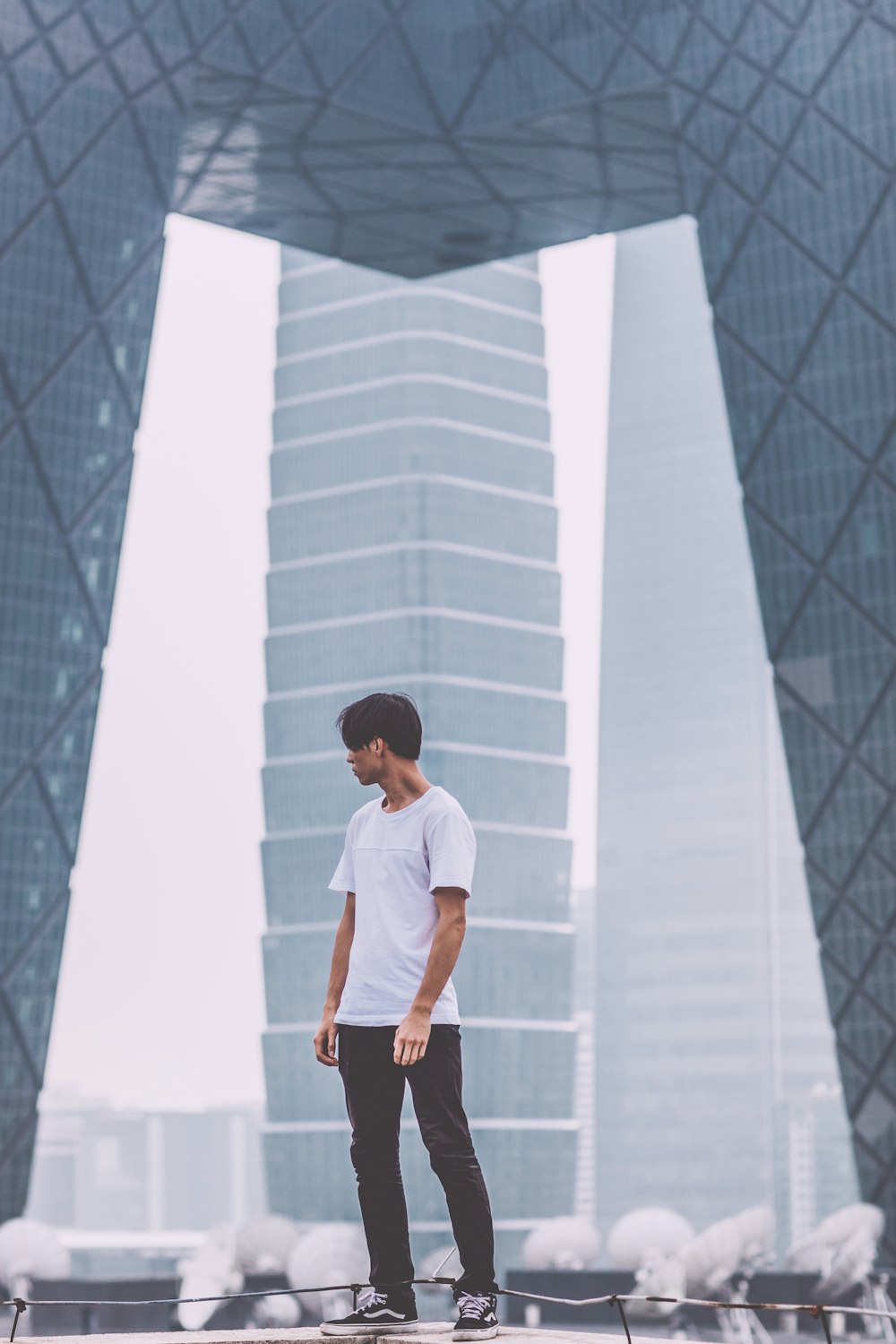 man wearing white crew-neck shirt standing near the building