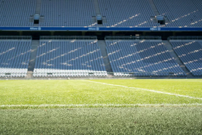 A vibrant college football field bathed in afternoon sunlight with empty stands ready for game day.