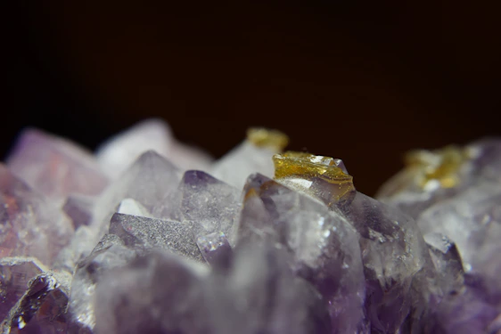Close-up of a deep purple amethyst crystal cluster glowing softly against a clean off-white background.