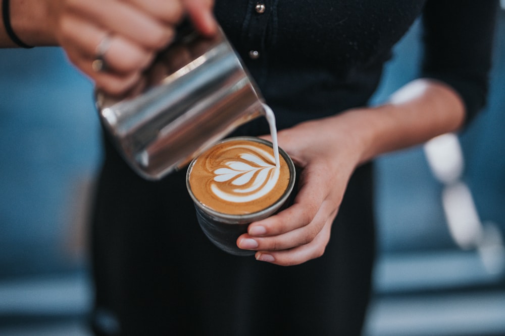 pessoa segurando café com xícara de café com leite