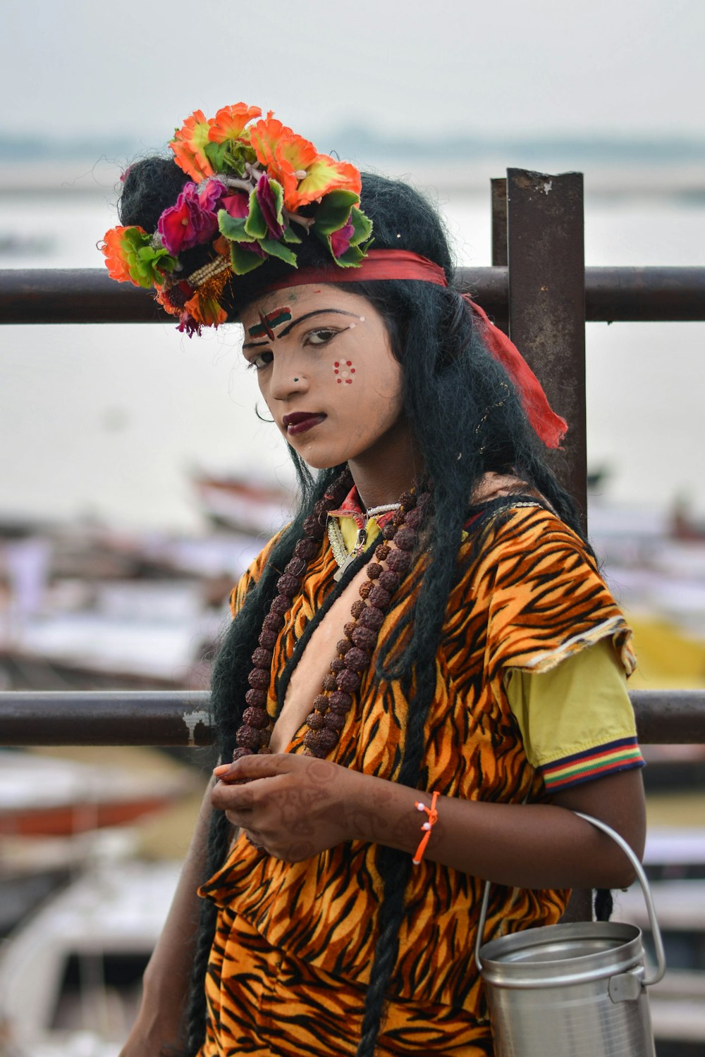 Mujer vestida con camisa amarilla, roja y naranja de pie junto a la valla de metal negro durante el día