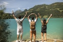 3 women in white tank top and black shorts standing on brown rock formation during daytime