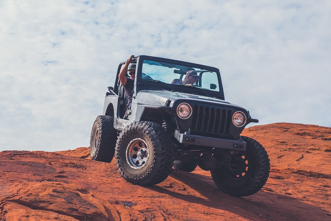 black Jeep Wrangler on brown field under cloudy sky during daytime