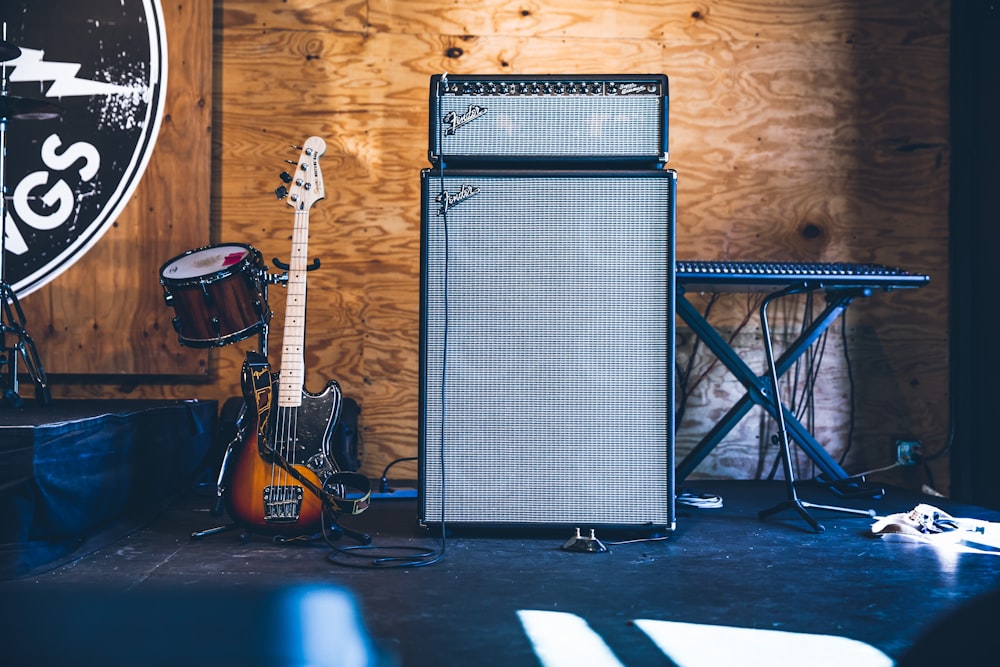 grey and black PA speakers near electric guitar and drum