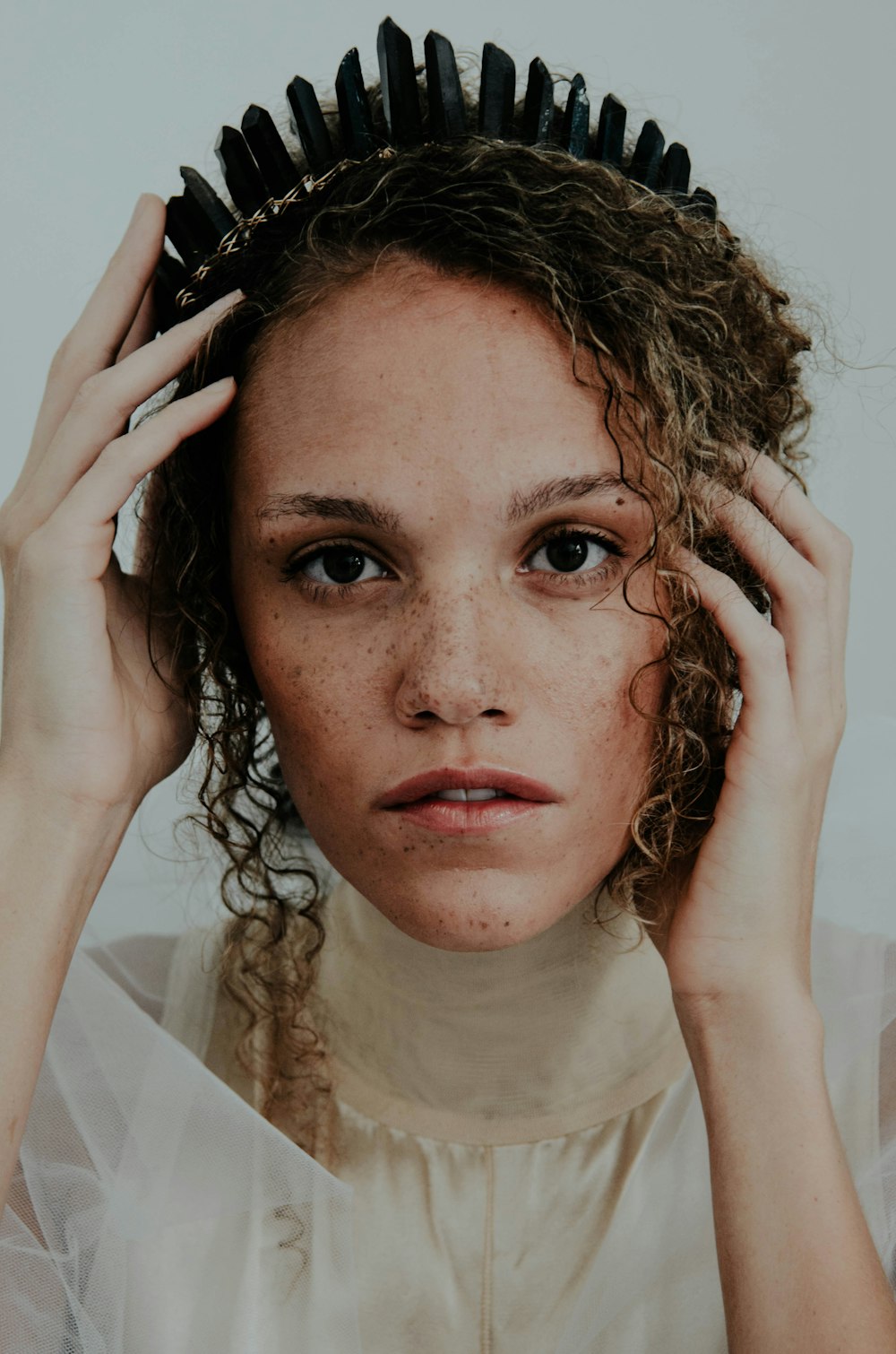 woman wearing white dress holding black crown