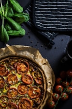 flat lay photography of two black pot holders beside tomatoes and pizza