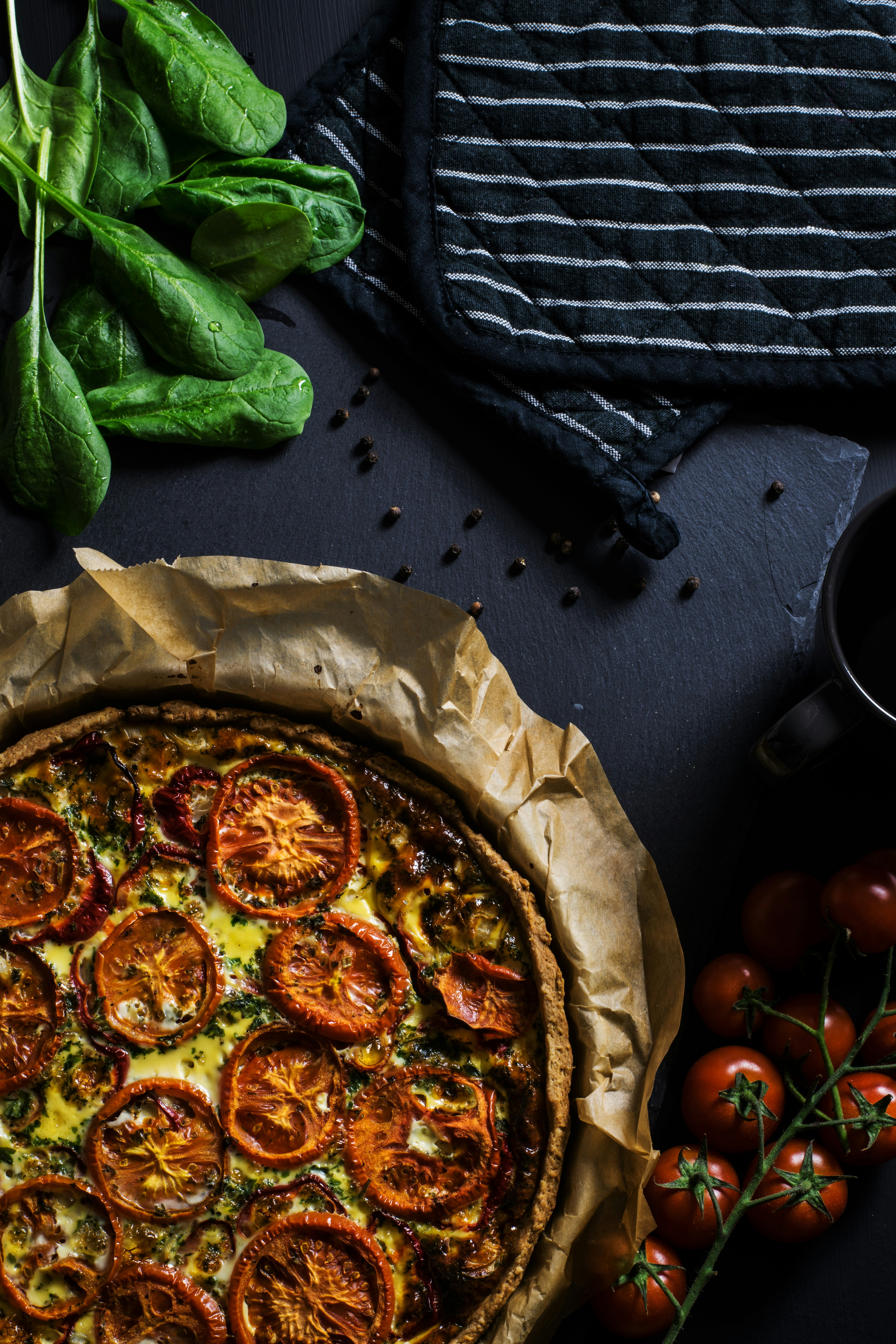 flat lay photography of two black pot holders beside tomatoes and pizza