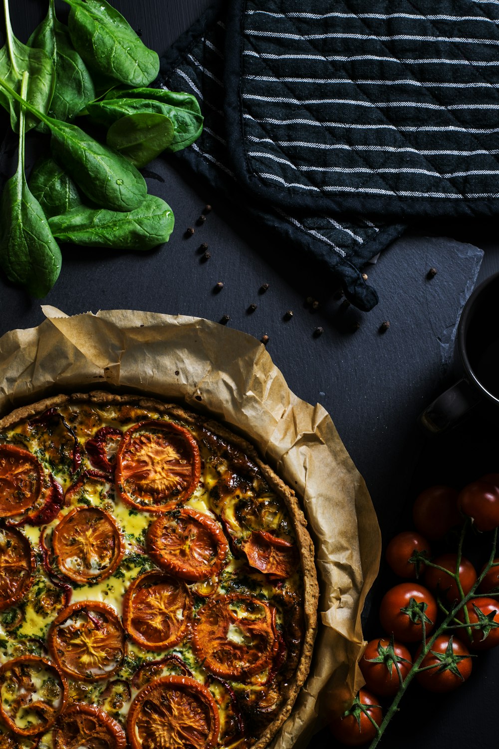 Fotografía plana de dos agarraderas negras junto a tomates y pizza
