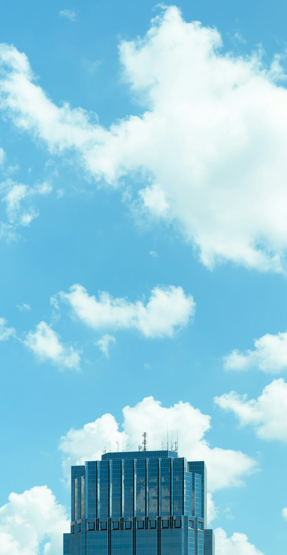 curtain wall high rise building under white clouds and blue sky