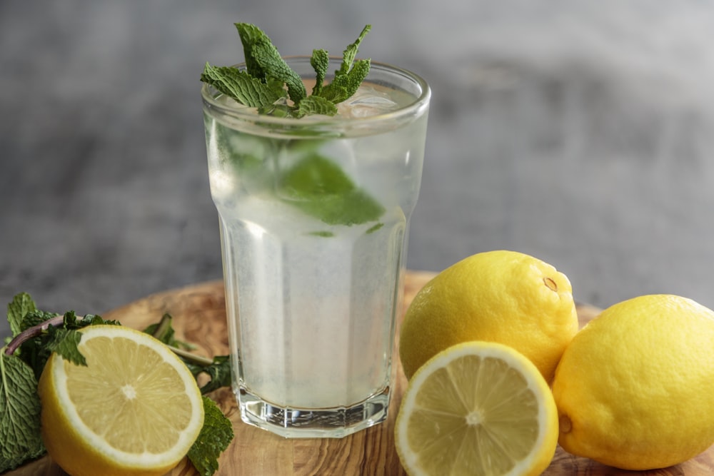 jus de citron vert sur un verre à boire à côté de citrons verts tranchés
