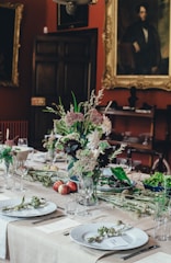 table arraignment with flower centerpieces and a man's portrait panting on nearby wall