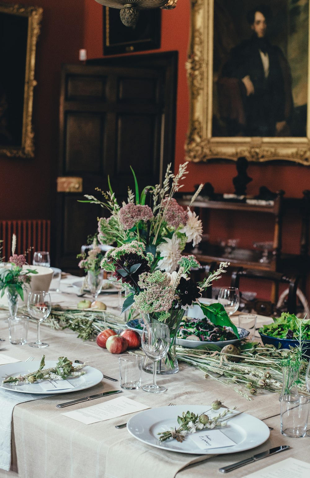 table arraignment with flower centerpieces and a man's portrait panting on nearby wall