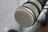 A close-up of a professional microphone with a metal mesh grille, highlighting the intricate pattern of the mesh. The microphone is positioned at an angle with a blurred background, providing a sense of depth.