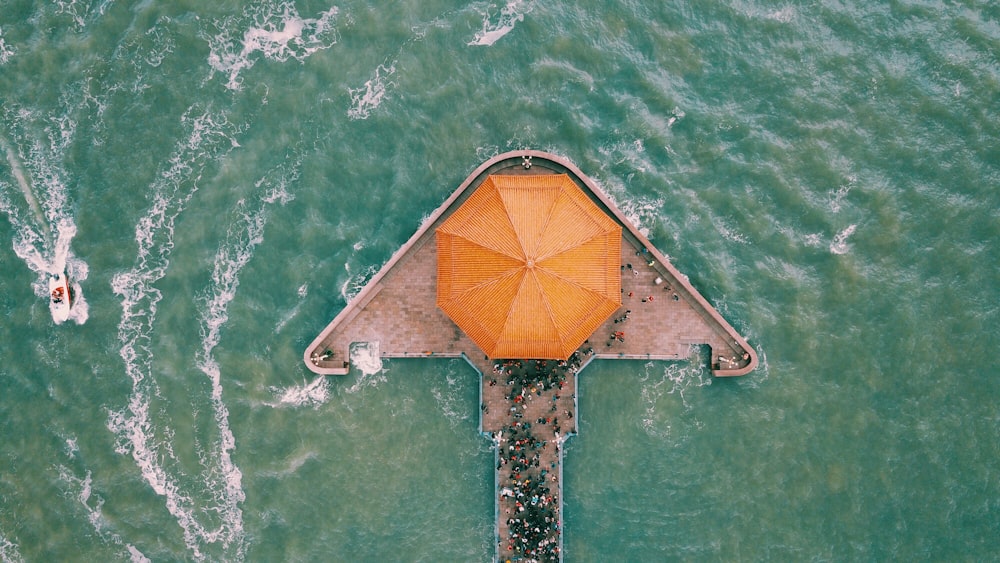 Fotografía aérea de un edificio gris y naranja en medio del mar