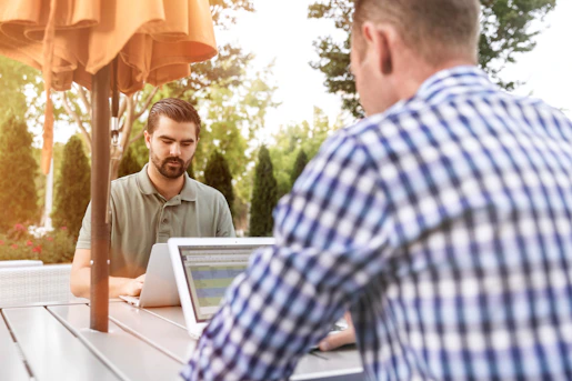 two person sitting on patio table using laptop computer