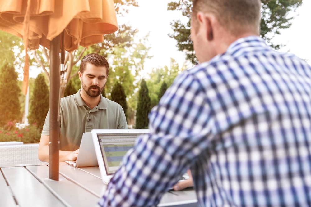 two person sitting on patio table using laptop computer