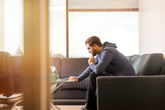 A confident man in his 40s working on a laptop at a sunlit home office, embodying focus and purpose.