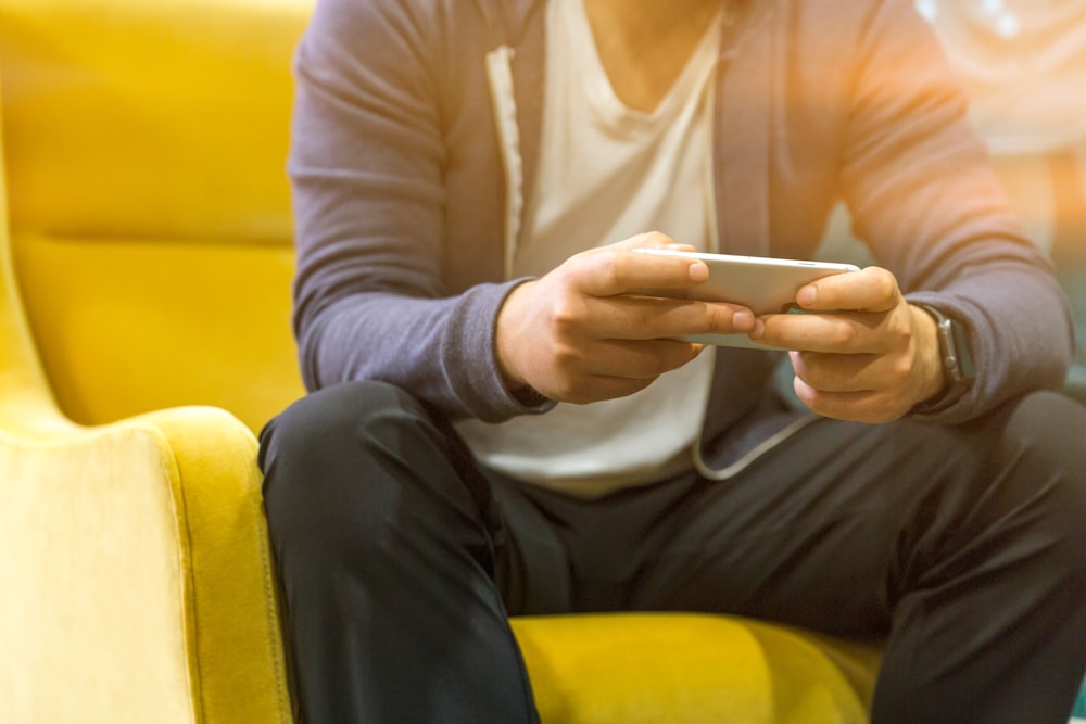 person holding smartphone sitting on couch