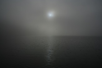 A misty Scottish loch at dawn with soft light reflecting on the water.