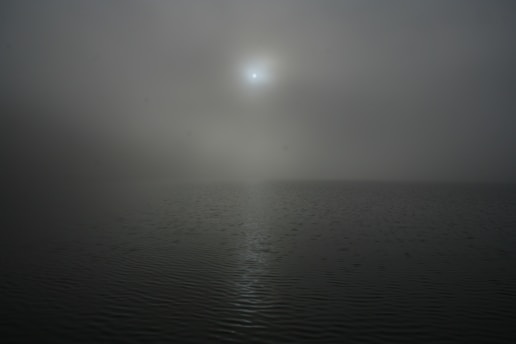 A misty Scottish loch at dawn with soft light reflecting on the water.