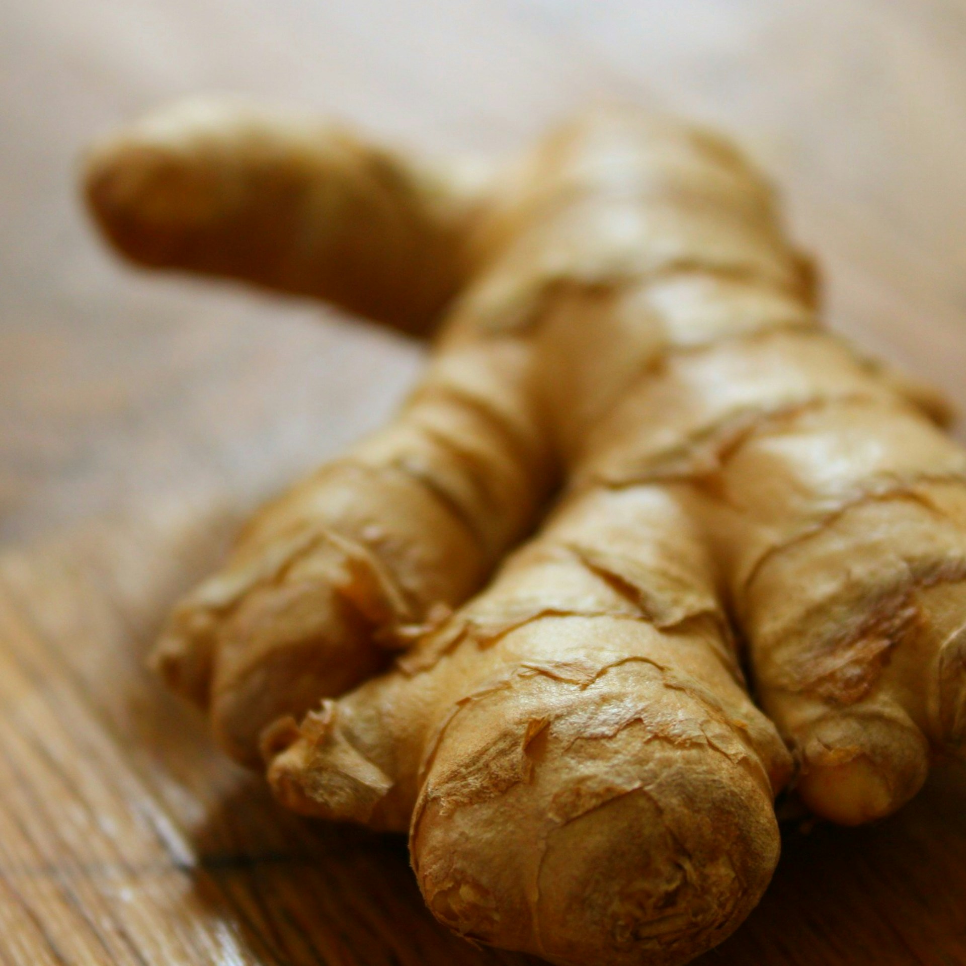 Fresh ginger root pieces on wooden surface, knobby tan skin