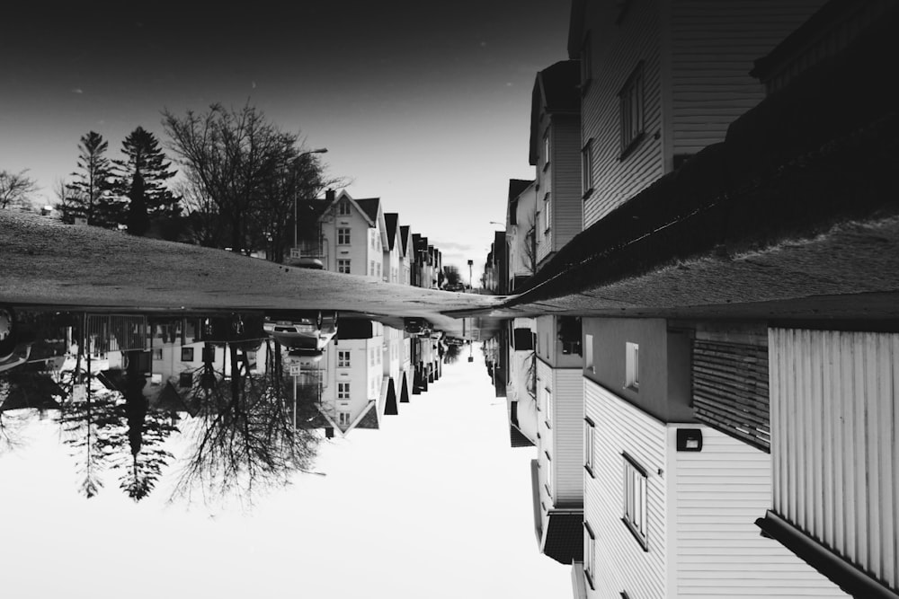 grayscale photo of house near street reflects on body of water