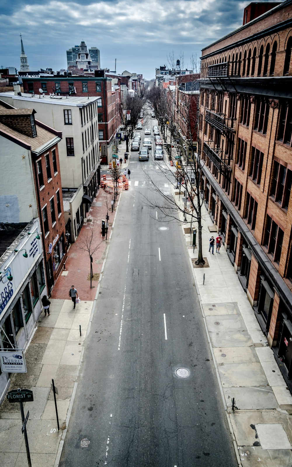 bird's-eye view photo of row of vehicles on concrete street in between of buildings