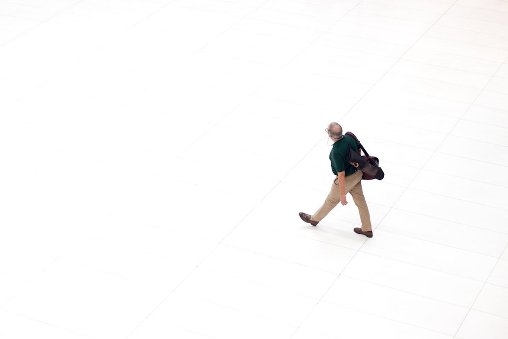 man with bag walks on white pavement