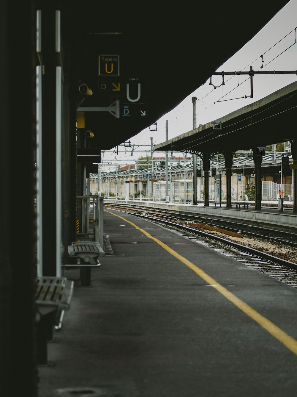 empty benches on train station beside railway at daytime