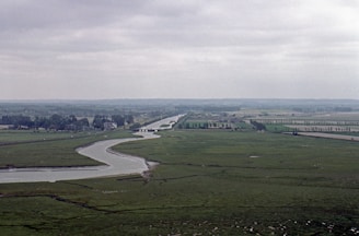A winding river cutting through rolling hills under a cloudy sky.
