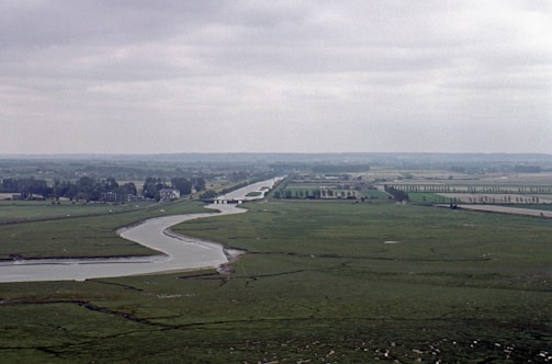 A winding river cutting through rolling hills under a cloudy sky.