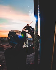 Workers welding steel plates during a ship repair at dusk with sparks flying.