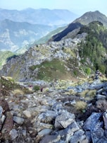 The rugged mountains of Ladakh under a clear blue sky with a group of trekkers on a trail.