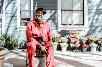 man sitting on concrete stool near teal building during daytime